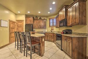 una cocina con armarios de madera y una isla con taburetes. en Luxurious Cedar City Getaway 32 Mi to Brian Head! en Cedar City