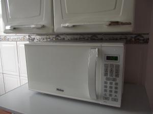 a white microwave on a counter in a kitchen at Apartamento Temporada in São Vicente