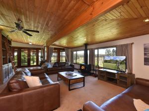 a living room with leather furniture and a flat screen tv at Soldiers Cottage picturebook vineyard home in Bulga
