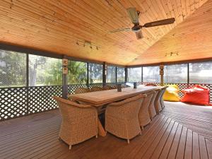 a dining room with a table and chairs on a deck at Soldiers Cottage picturebook vineyard home in Bulga