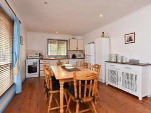 a kitchen with a table and chairs and a refrigerator at Wallaby Cottage in Ellalong
