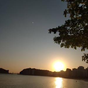 a sunset over a body of water with a city at Apartamento Temporada in São Vicente