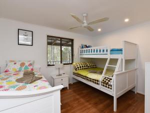 a bedroom with two bunk beds and a ceiling fan at Australiana Cottages in Ellalong