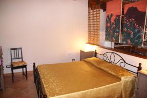 a bedroom with a bed and a chair in it at La Finestra Sotto La Rocca in Cefalù