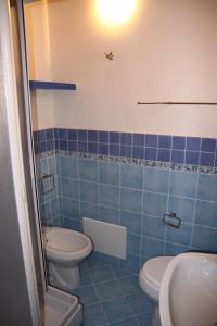 a blue tiled bathroom with a toilet and a sink at La Finestra Sotto La Rocca in Cefalù