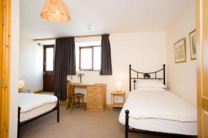 a bedroom with two beds and a desk and a window at Rye Hill Farm in Hexham