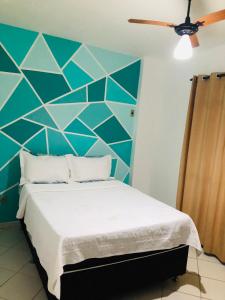 1 dormitorio con 1 cama con pared azul en Solares | Verdes Mares, en Arraial do Cabo