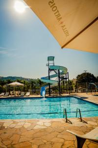 a swimming pool with a water slide in the background at Hotel Fazenda Ramon in São Lourenço