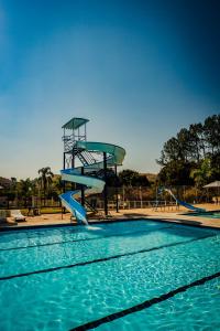 a slide in a swimming pool with blue water at Hotel Fazenda Ramon in São Lourenço