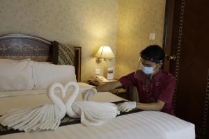 a man in a mask making swans on a bed at Ambhara Hotel in Jakarta