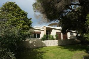 a white house with a fence in a yard at Baillieu Breeze in Point Lonsdale