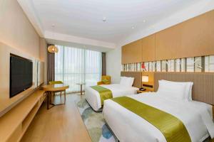a hotel room with two beds and a flat screen tv at Holiday Inn Changsha Dawangshan, an IHG Hotel in Changsha