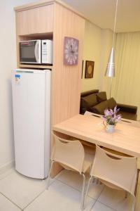 Il comprend une cuisine équipée d'un réfrigérateur blanc et d'une table avec des chaises. dans l'établissement 304 Flat Edifício Everest, à Caldas Novas