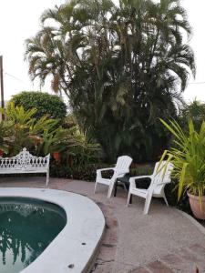 two white chairs sitting next to a swimming pool at Departamentos con Alberca in Mazatlán