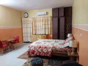 ein Schlafzimmer mit einem Bett, einem Tisch und einer Uhr in der Unterkunft Appartement ABS in Abidjan