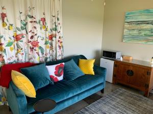 a living room with a blue couch with colorful pillows at Mangawhai Bay B&B in Omokoroa