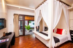 a bedroom with a white canopy bed with red pillows at Pao Jin Poon Villa in Lamai