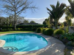 a swimming pool in a yard with trees and plants at Mangawhai Bay B&B in Omokoroa