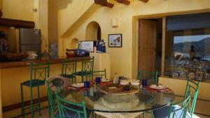 a kitchen with a glass table and green chairs at preciosa casa que ve al pacifico in Zihuatanejo