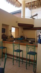 una cucina con tre sedie verdi e un bancone di preciosa casa que ve al pacifico a Zihuatanejo