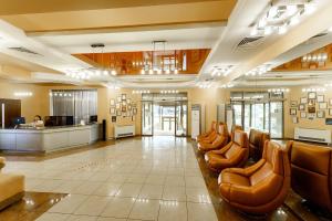 a lobby with brown leather chairs and a counter at Hotel Briz in Orenburg
