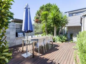a table with a blue umbrella and chairs and a table with at Hahei Beach House - 3 Bedroom in Hahei