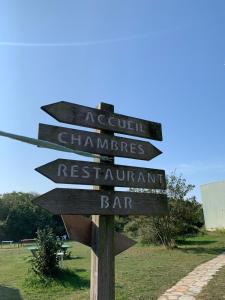 un panneau en bois avec des flèches pointant dans différents sens dans l'établissement Auberge de Jeunesse HI Belle-Île-en-Mer, au Palais