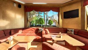 a living room with a couch and tables and a tv at Family Hotel Emaly 1 in Bankya