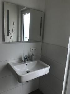 a white bathroom with a sink and a mirror at Ferienhaus SEE & Ferienhaus SEEBLICK in Neukieritzsch