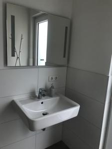 a white bathroom with a sink and a mirror at Ferienhaus SEE & Ferienhaus SEEBLICK in Neukieritzsch +11 photos