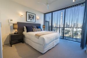 - une chambre avec un grand lit et une grande fenêtre dans l'établissement Arena Apartments by CLLIX, à Brisbane