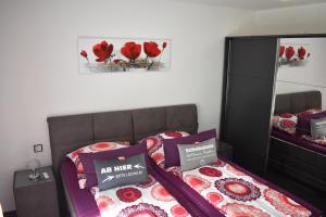 Schlafzimmer mit einem Bett, einem Spiegel und roten Blumen in der Unterkunft FEWO Excellence in Traben-Trarbach
