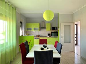 a kitchen with green cabinets and a white table and chairs at Apartment Rozi in Šilo