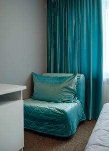 a bed with a blue pillow next to a window at ГК Аэродром Танай in Vaganovo