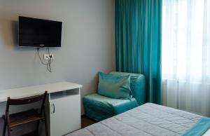 a room with a bed and a chair and a television at ГК Аэродром Танай in Vaganovo