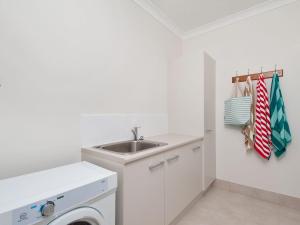 a white laundry room with a sink and a washing machine at Calm at Shoal Bay in Shoal Bay