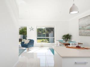 a white kitchen with a blue chair and a table at Calm at Shoal Bay in Shoal Bay