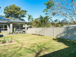 a fence in front of a house with a yard at Calm at Shoal Bay in Shoal Bay