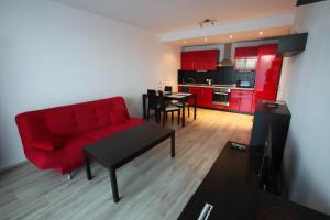 a living room with a red couch and a kitchen at Apartment Park Radouč - 60m2 in Mladá Boleslav