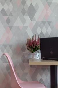 a desk with a laptop and a pink chair at INITIUM rooms - Pokoje na wynajem - Obrońców Wybrzeża 4D in Gdańsk