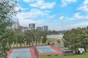 a group of tennis courts with a city in the background at KOZYGURU WOLLI CREEK KOZY 1 BED APT SYDNEY AIRPORT & SYDNEY CBD NWC020 in Sydney
