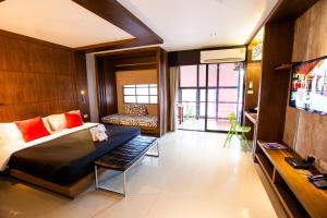 Amenity Apartel Samui في شاطئ لاماي: غرفة نوم بسرير وتلفزيون وأريكة