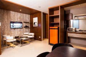 a living room with a table and chairs and a kitchen at Amenity Apartel Samui in Lamai