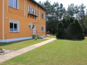 an orange building with a grass yard next to a house at Ferienwohnung am alten Gutshaus in Nossentin