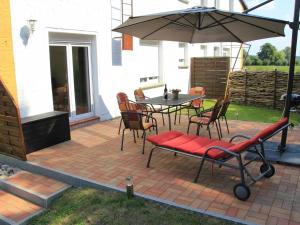 a patio with a table and chairs and an umbrella at Ferienwohnung am alten Gutshaus in Nossentin