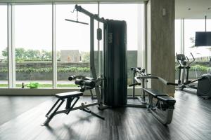 a gym with two tread machines in a room with windows at Lavish 1BR at Ciputra International Apartment By Travelio in Jakarta
