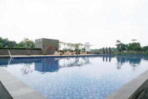 a large swimming pool with blue water at Lavish 1BR at Ciputra International Apartment By Travelio in Jakarta