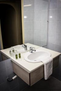 ein Bad mit einem Waschbecken und einem Spiegel in der Unterkunft Le Terminus in Tarascon