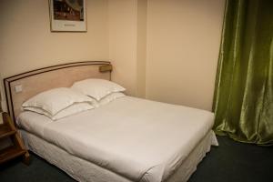 Bett mit weißer Bettwäsche und Kissen in einem Zimmer in der Unterkunft Le Terminus in Tarascon