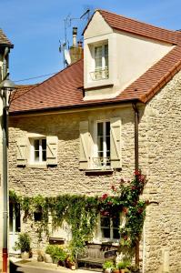 een oud stenen huis met twee ramen en bloemen bij Petit Montrachet in Chassagne-Montrachet